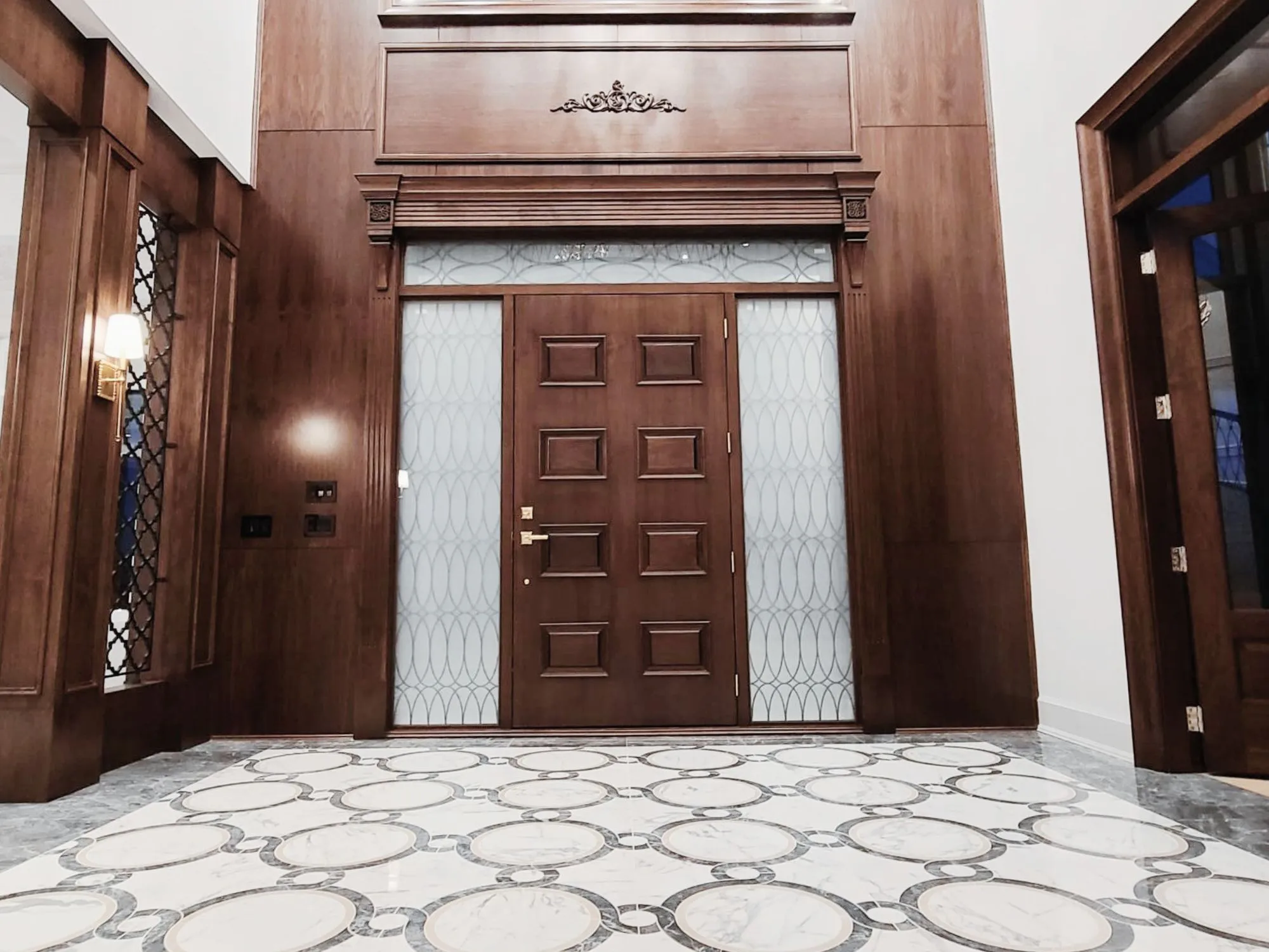A lavish home entrance featuring a wooden door and marble floor.